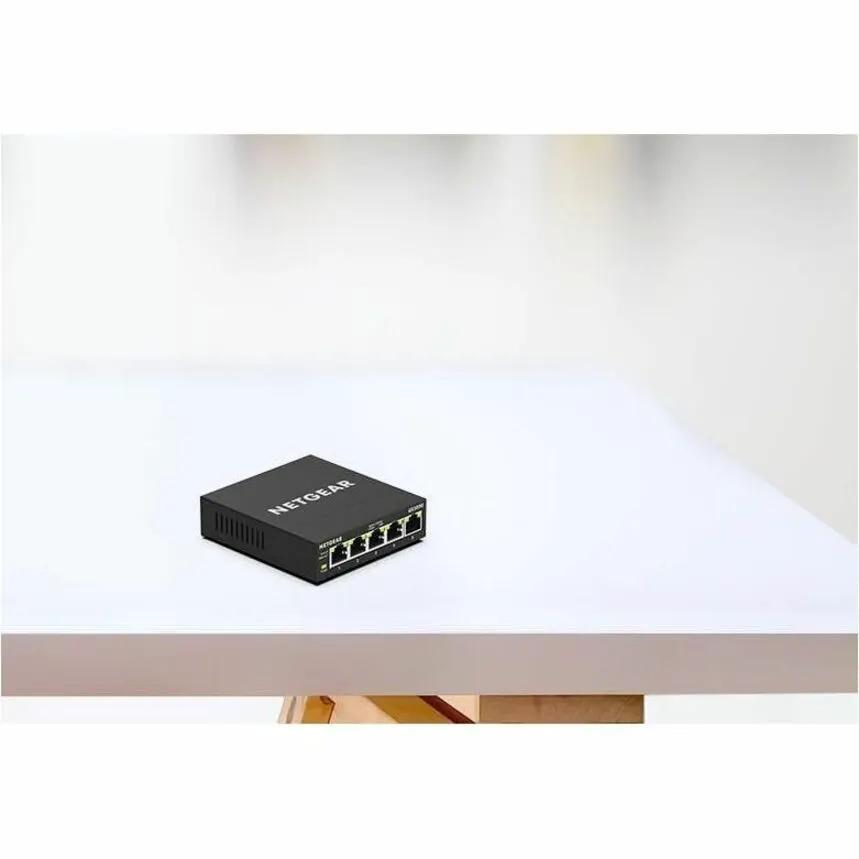 Netgear Plus GS305E 5-Port Managed Switch, black on white table.