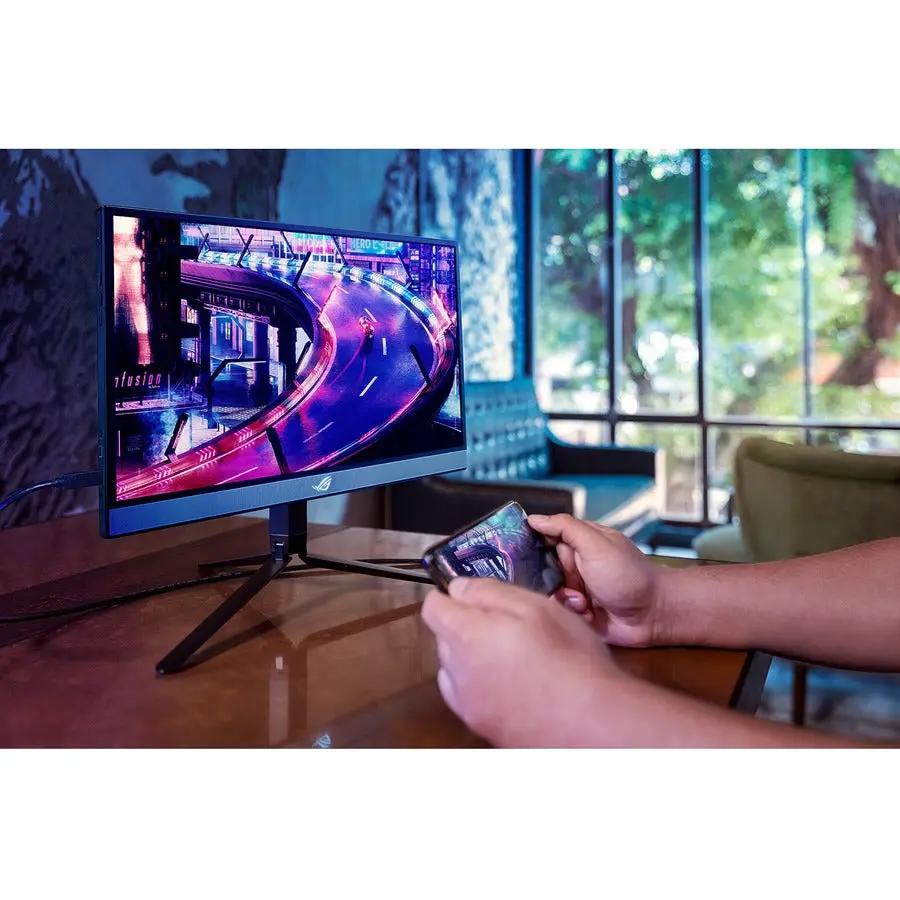 ASUS ROG Strix XG17AHP 17-inch FHD IPS gaming monitor on a desk, with a person holding a smartphone nearby.