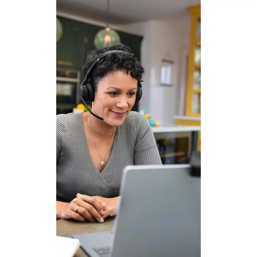 Jabra Evolve2 55 headset, black over-ear with mic, worn by a woman at a laptop in an office.