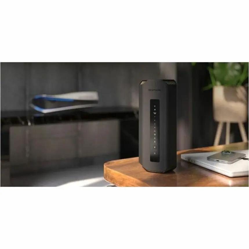 Netgear Nighthawk RS700S wireless router, black vertical design with LED indicator strip on a wooden table.