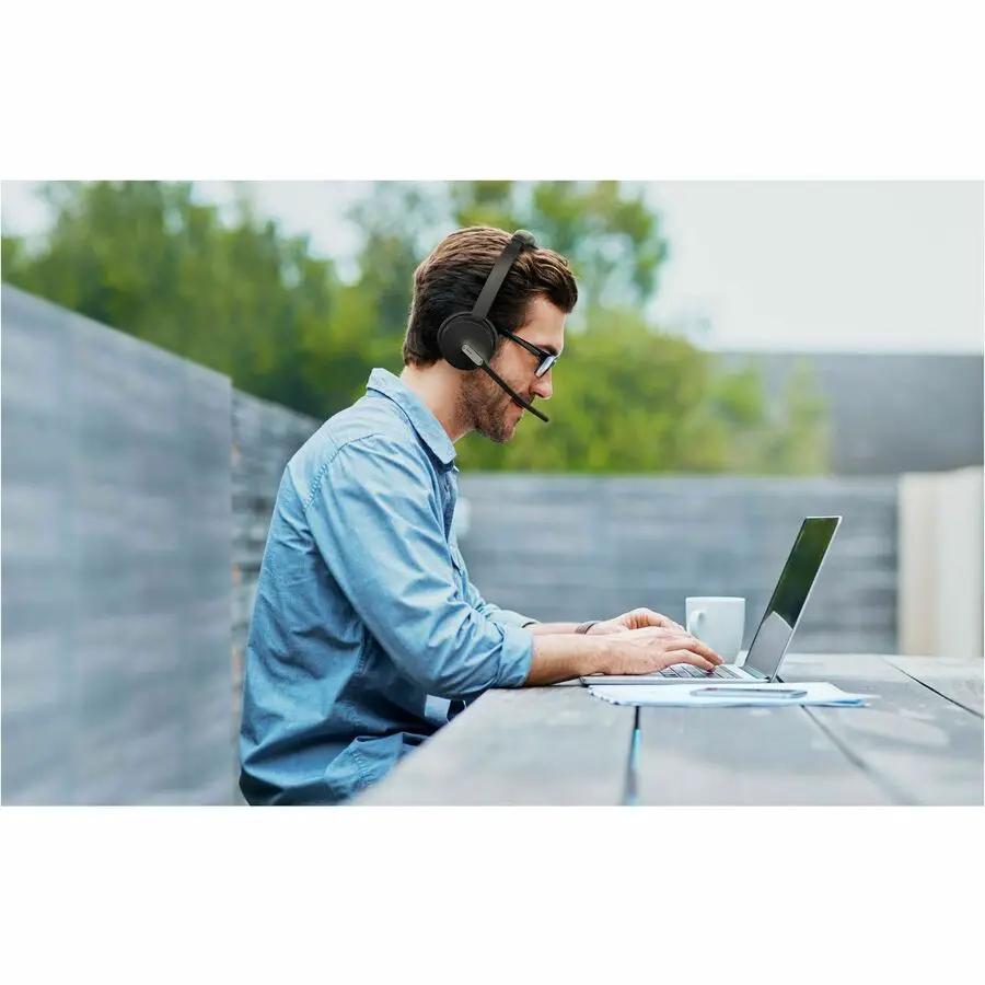 YeaLink BH70 mono USB-A headset worn by man at outdoor laptop desk.