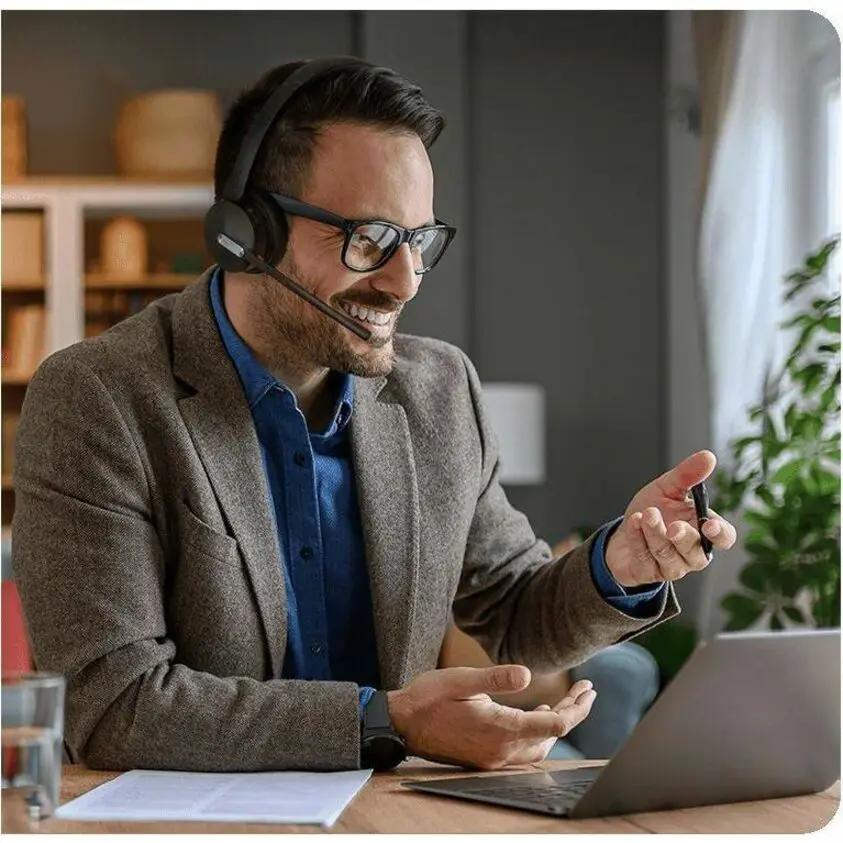 Yealink WH64 Hybrid Mono UC wireless headset, black, worn by a man at a desk with a laptop.