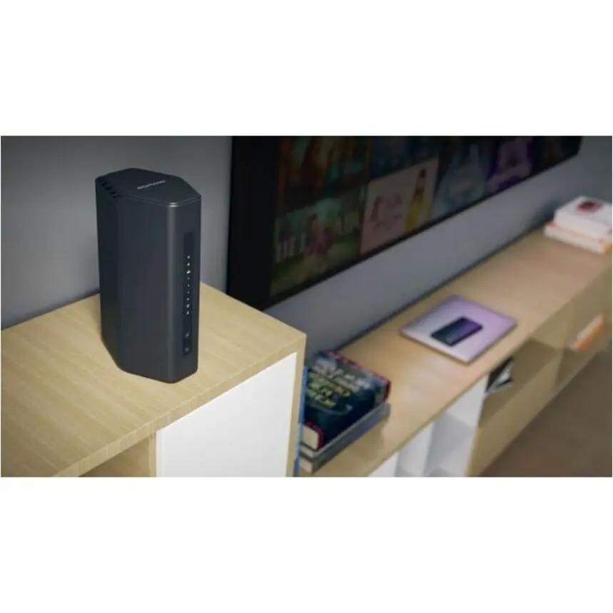 Netgear Nighthawk RS200 router, black, standing upright on a wooden shelf beside a TV.