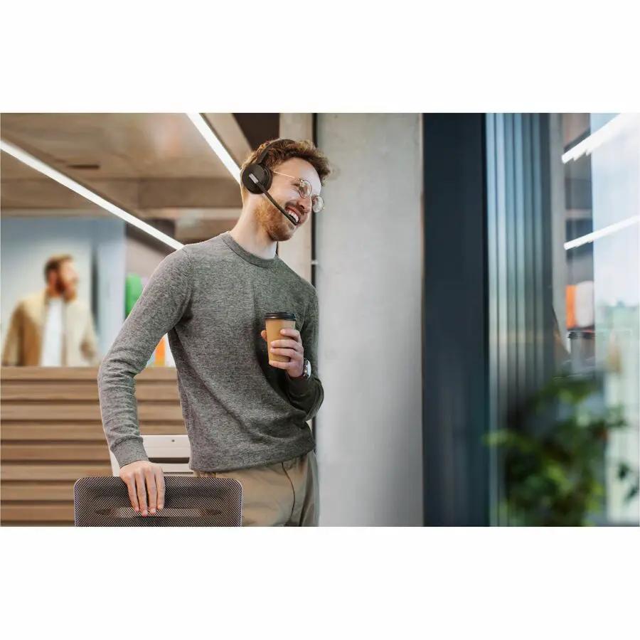Yealink BH70 wireless headset with boom mic, black, worn by person in office.