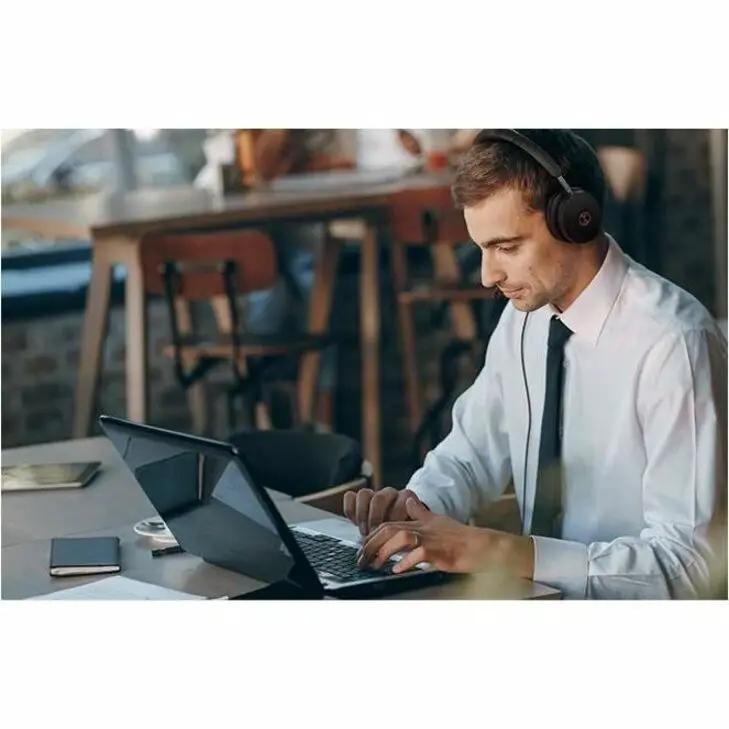 Yealink UH48 Dual MS USB-C/A headset, black, worn by a man at a laptop in a cafe.