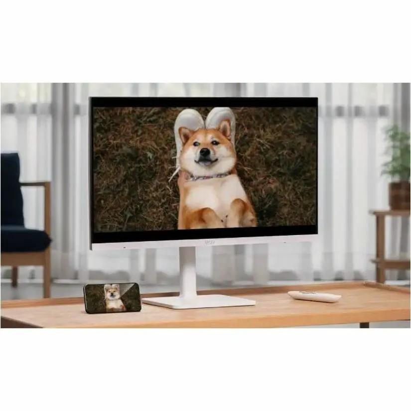 MSI Modern MD272UPSW 27-inch UHD monitor and smartphone on a wooden desk in a bright living room displaying a dog image