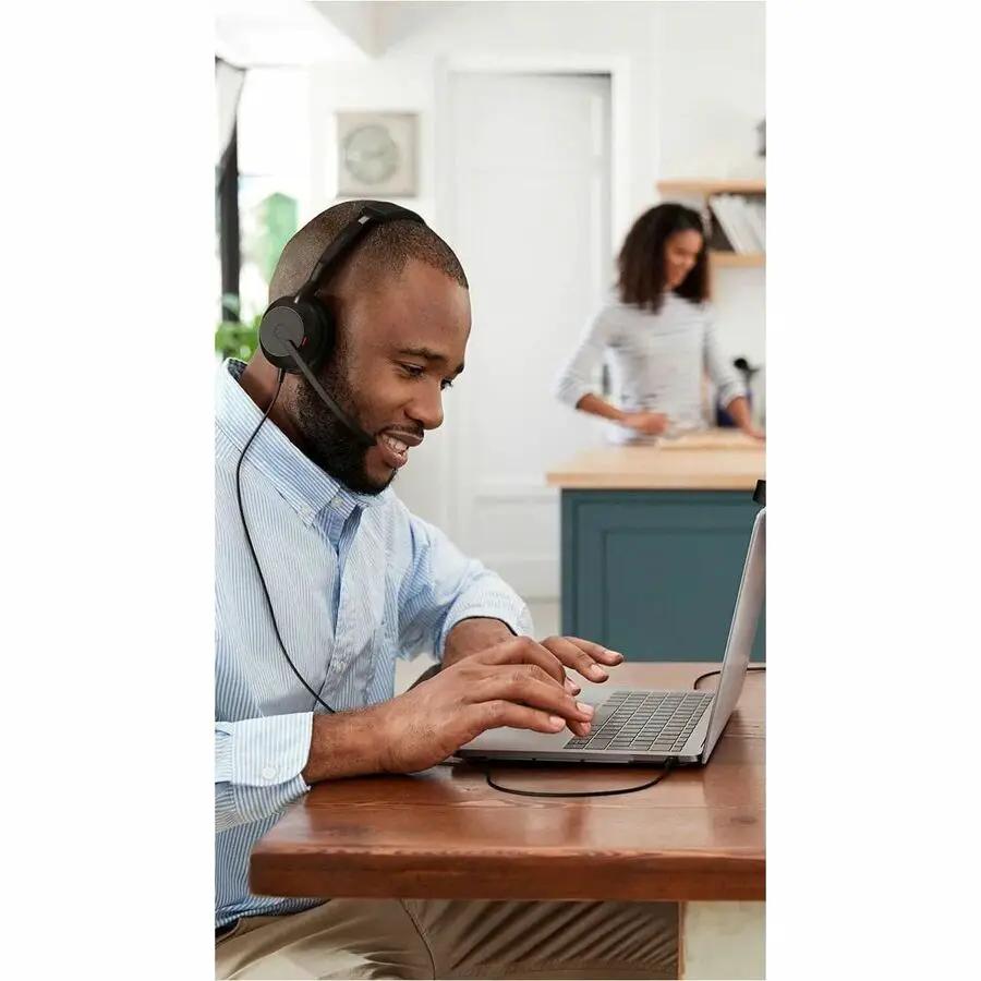 Jabra Evolve2 50 wireless headset worn by a man using a laptop at a wooden table
