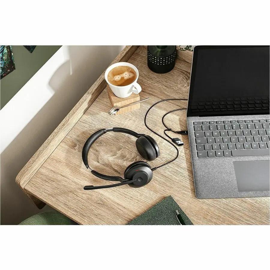 Jabra Evolve2 30 SE black headset on a wooden desk beside a laptop