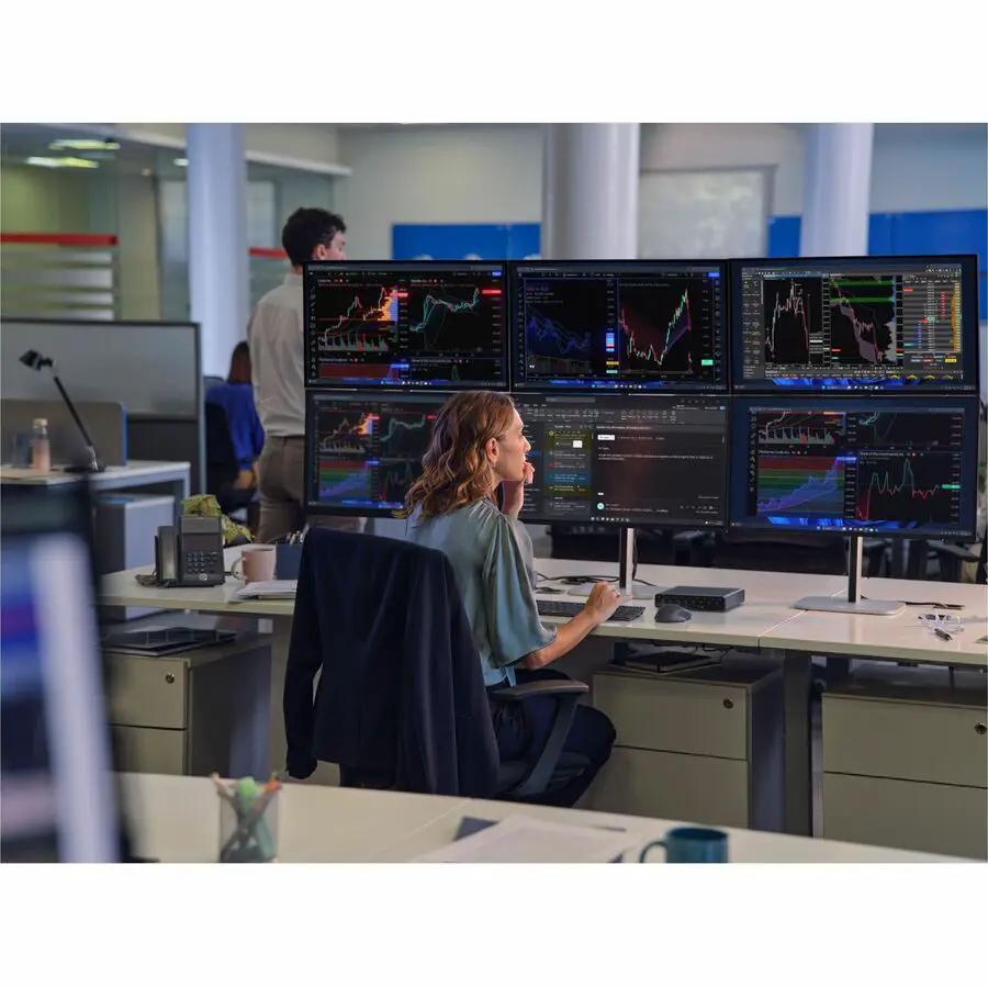 Desktop workstation with six monitors displaying stock charts in a busy office.
