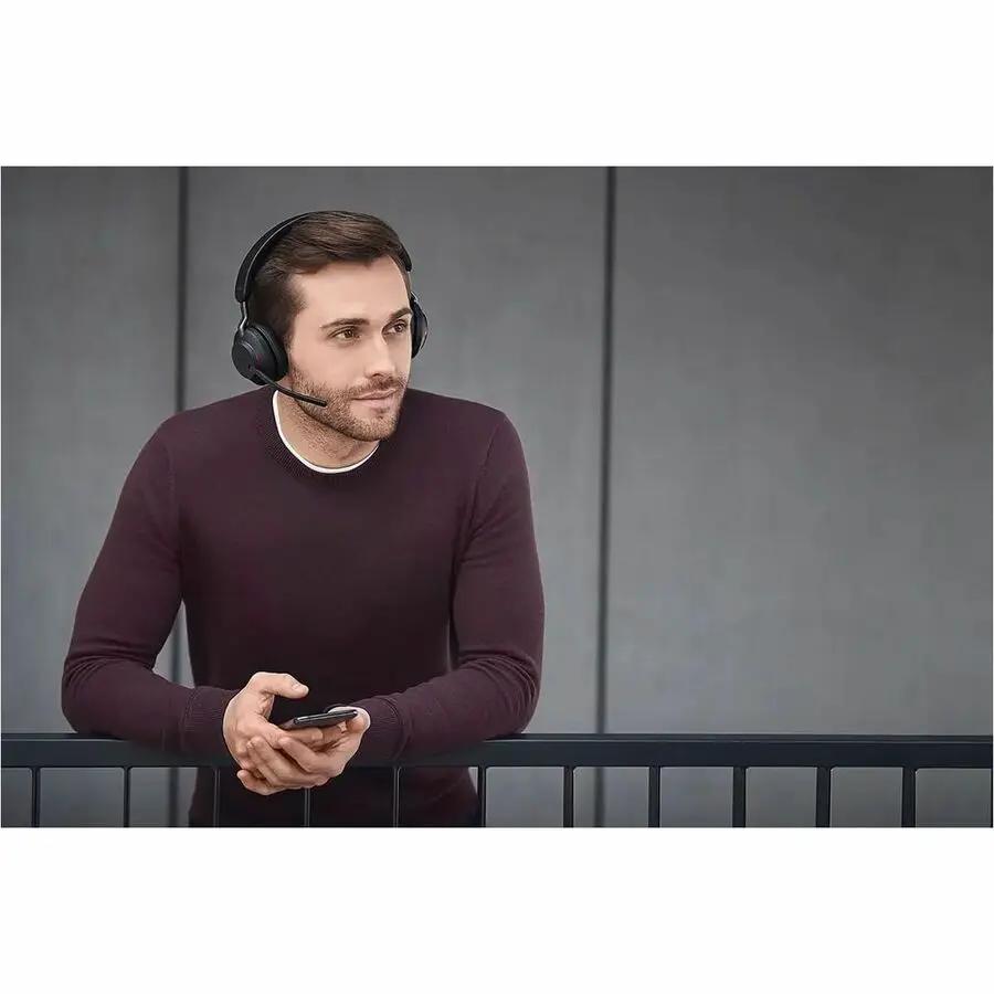 Jabra Evolve2 65 USB MS Mono headset worn by a man in a maroon sweater, standing by a railing.