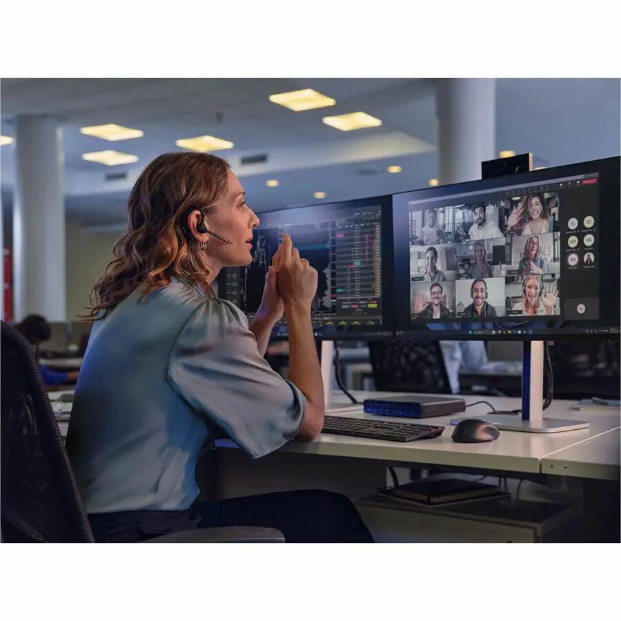 Desktop computer setup with dual monitors displaying a video conference, headset on a white desk