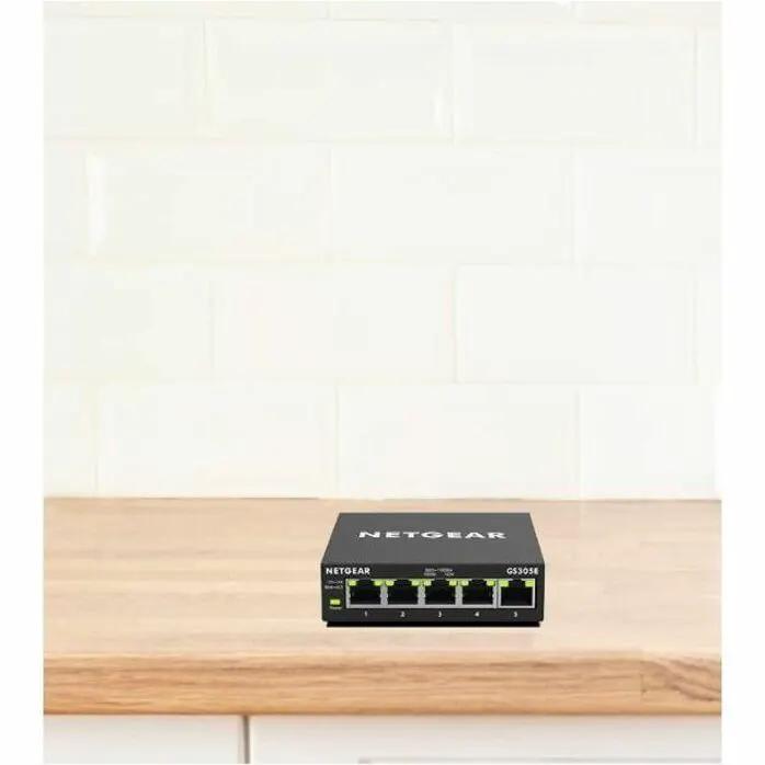 Netgear Plus GS305E 5-Port Managed Switch, black on wooden counter