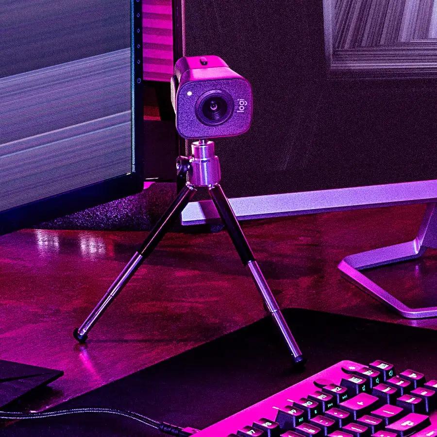 Stream Cam Plus Graphite webcam on a small tripod in a desk setup, Logitech Core branding visible