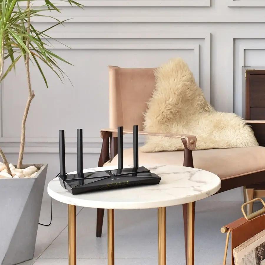 TP-Link Archer AX10 WiFi 6 router with four antennas on a white marble round table in a living room