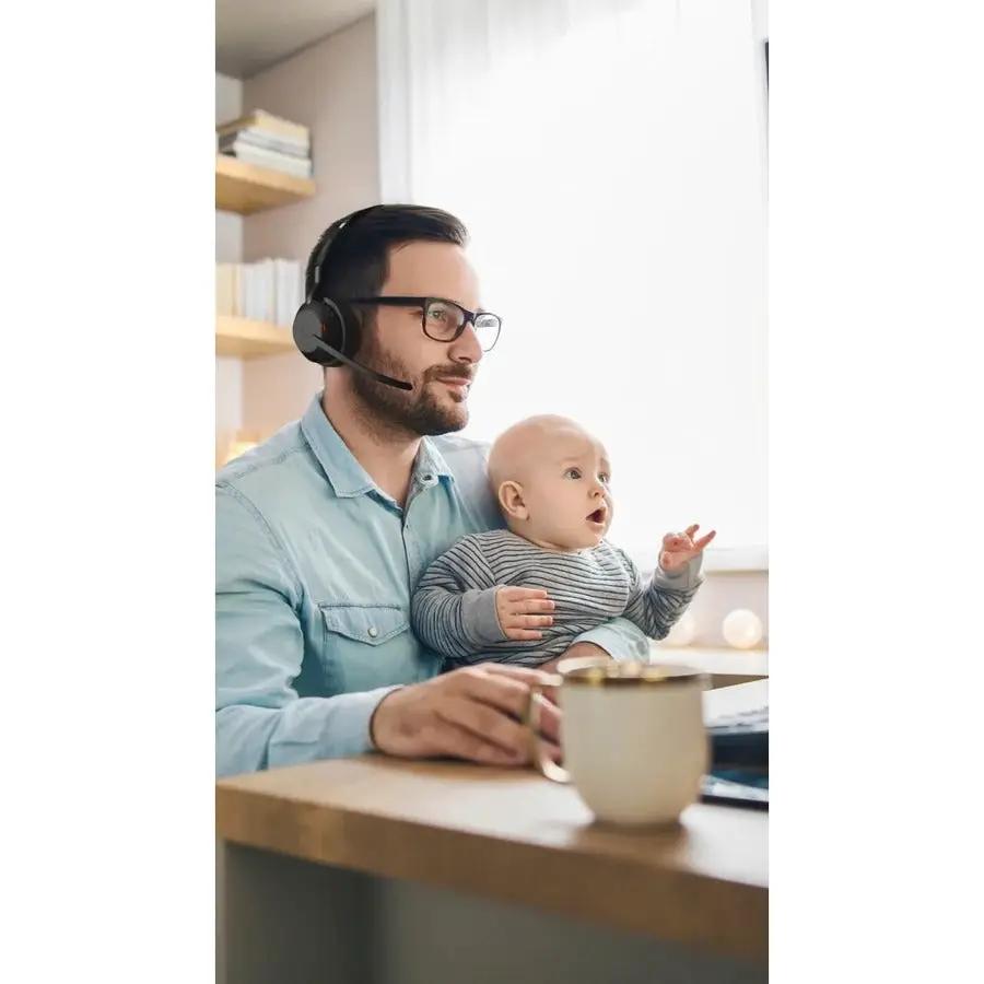Jabra Evolve2 55 black headset worn by man at desk holding a baby