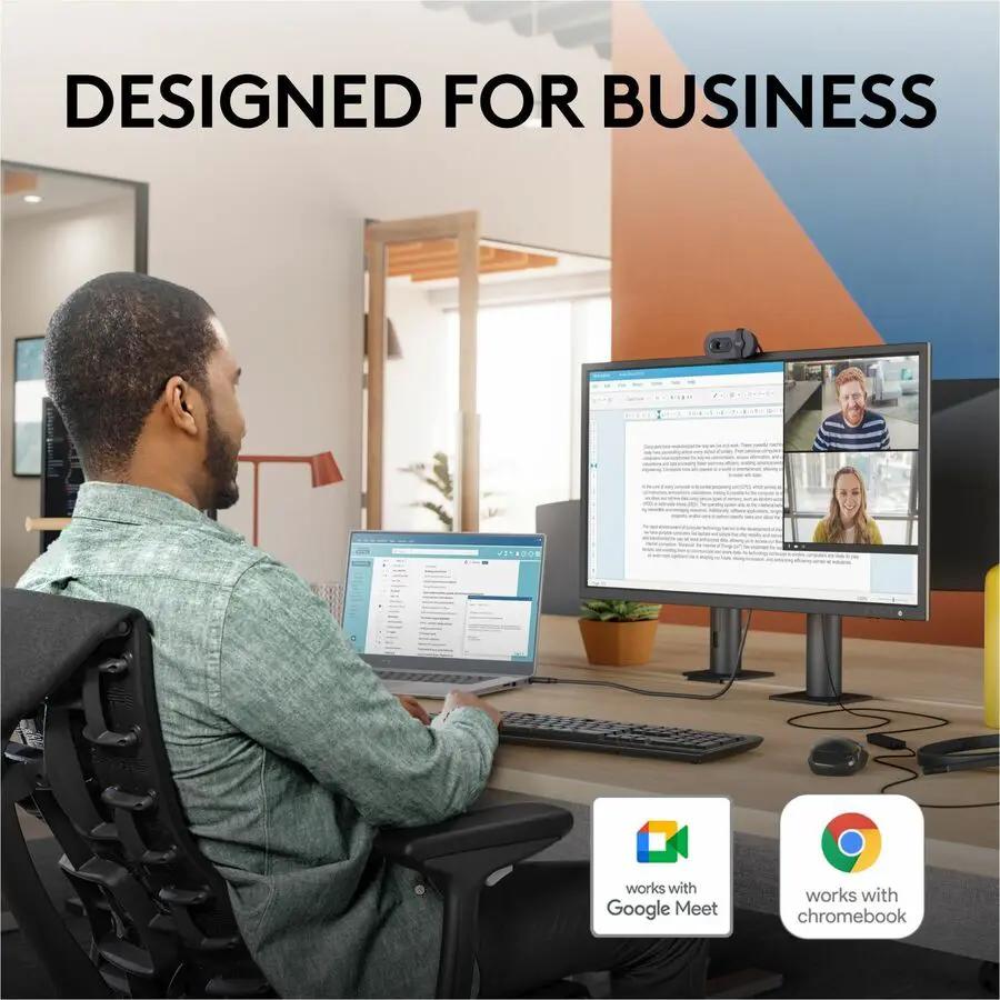 Brio 105 webcam on desk with dual monitors; black device, Google Meet and Chromebook compatible