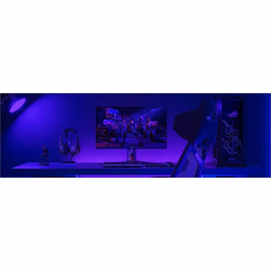 ASUS ROG Swift PG32UCDM 32-inch gaming monitor on a desk with keyboard, headset, and blue RGB lighting.