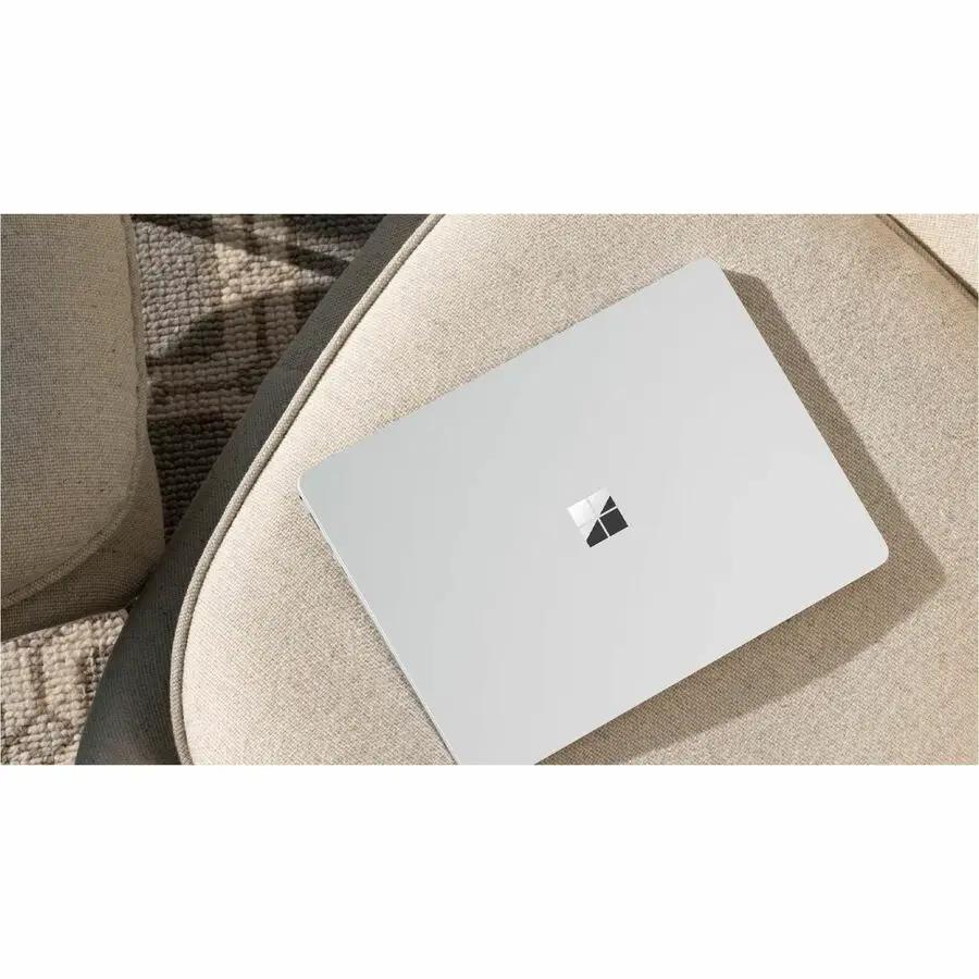 Microsoft Surface Laptop 7 15-inch silver laptop with Microsoft logo on a beige couch.