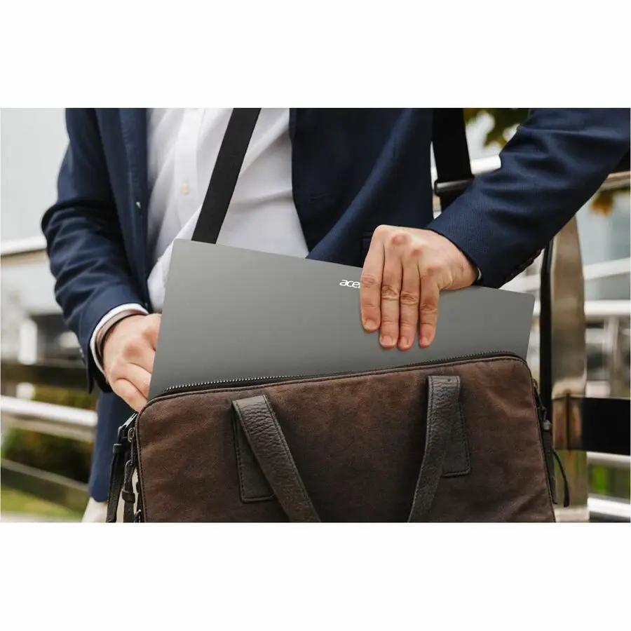 Acer Extensa 15 notebook, gray, being slid into a brown leather bag by a person in a suit.