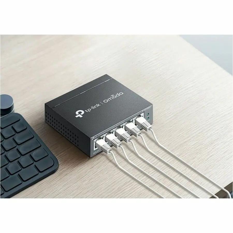 TP-Link Omada 5-Port Gigabit PoE+ managed switch on desk with five Ethernet cables connected
