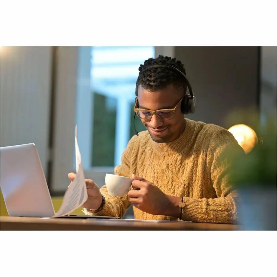 Yealink BH70 black headset worn by man at a desk with laptop and cup