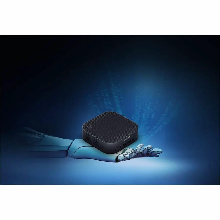 ASUS NUC 14 Pro AI Copilot Mini PC, black with a perforated top, resting on a robotic hand.