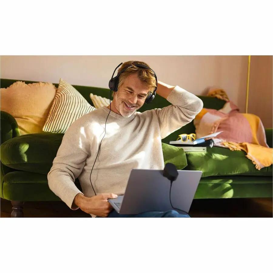 Jabra Evolve2 50 black headset on a man using a laptop on a green sofa