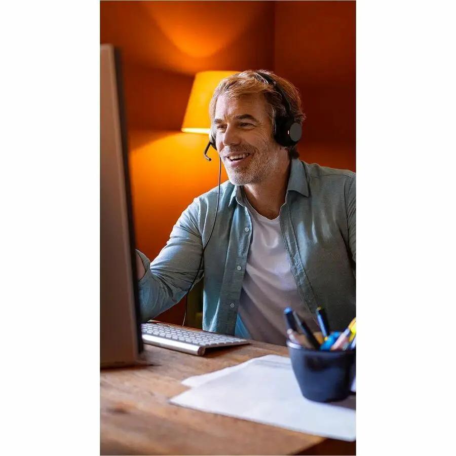 Jabra Evolve2 50 headset, black, worn by a man at a computer desk