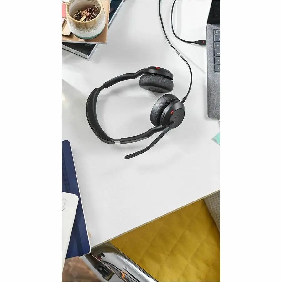 Jabra Evolve2 50 black headset on a white desk beside a laptop.