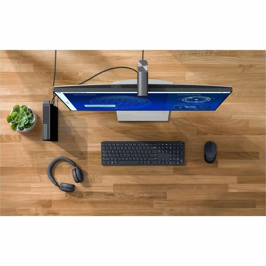Dell QBM1250 Pro Micro Plus Ultra-Compact PC, black, on a wooden desk beside monitor, keyboard, and mouse