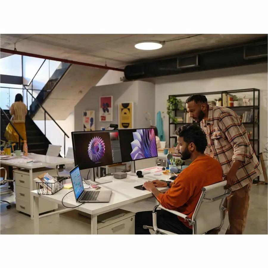 HP ZBook 14 laptop on a white desk in an office with dual monitors.