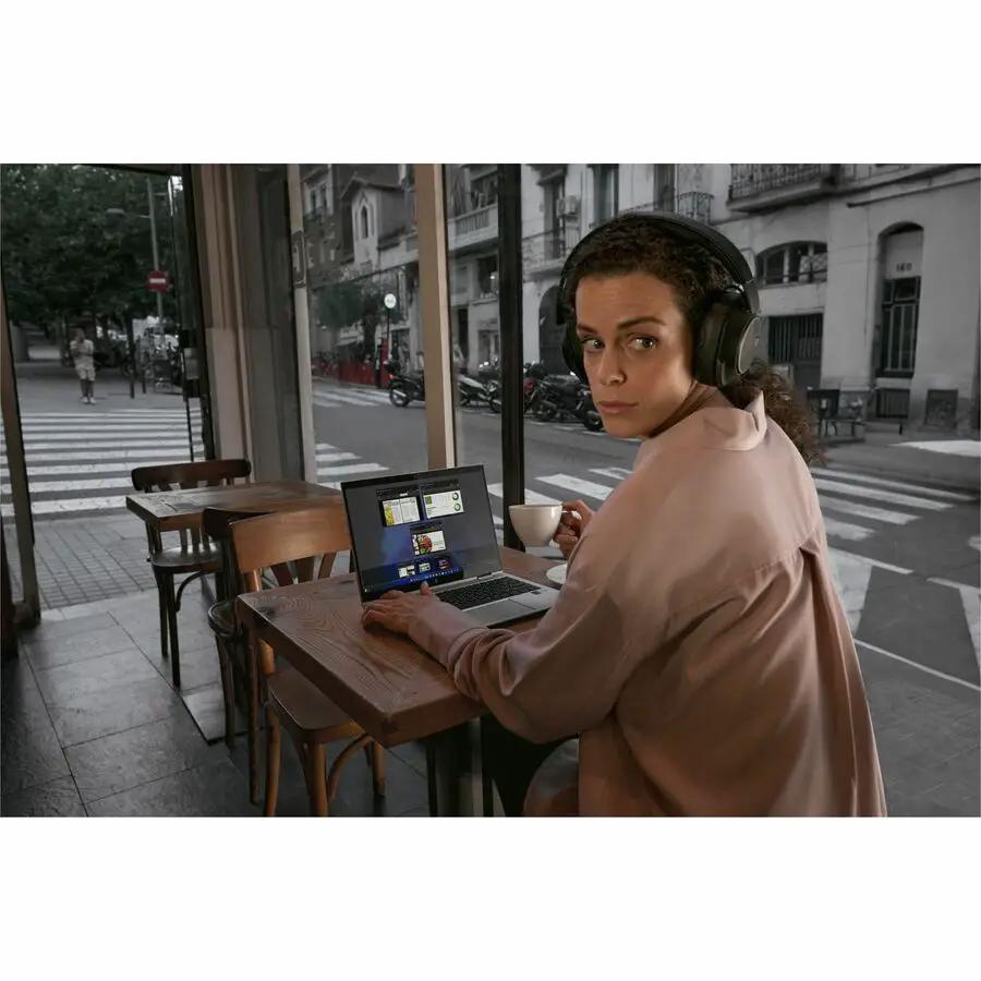 HP EliteBook notebook on a wooden cafe table with headphones.