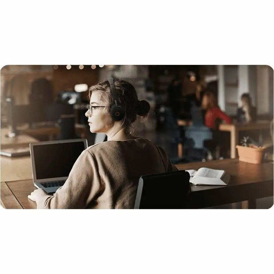 Yealink WH68 UC wireless over-ear headset in black, worn by a person at a desk with a laptop in an office.