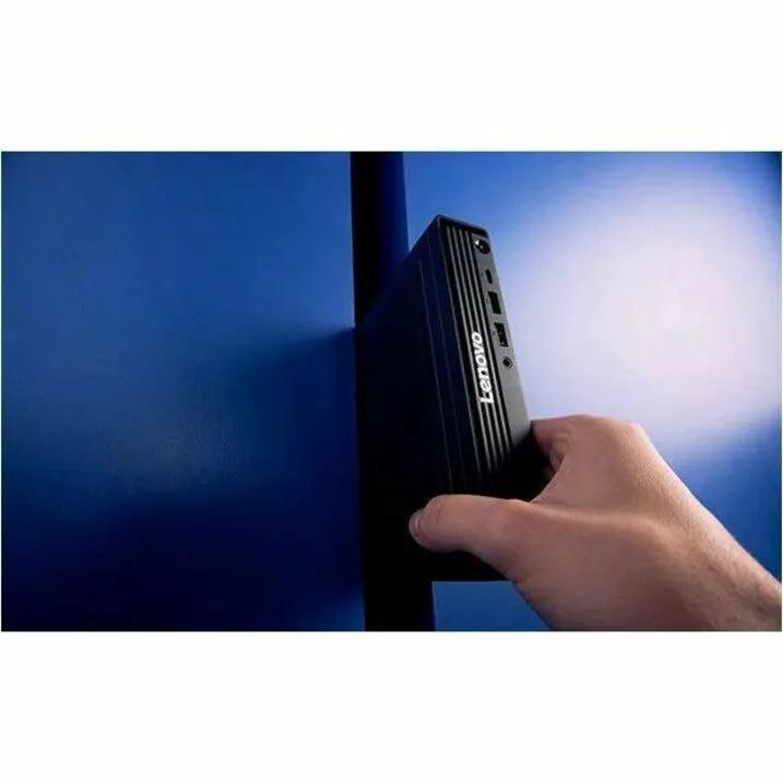 Lenovo ThinkCentre M90q Gen 6 mini desktop, black, handheld beside blue wall