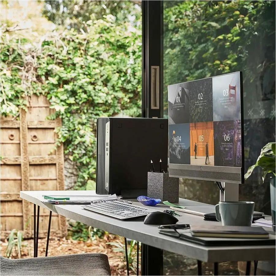 HP EliteDesk 8 G1i desktop tower, black, on a desk beside a monitor in a bright home office.
