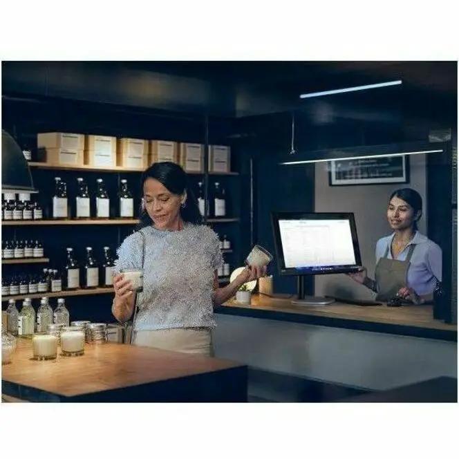Bar counter scene with a touchscreen POS monitor behind the counter; a woman holding a drink.