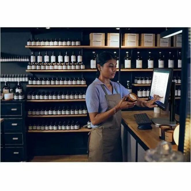 All-in-one desktop computer with a black touchscreen monitor on a store counter, shelves in the background