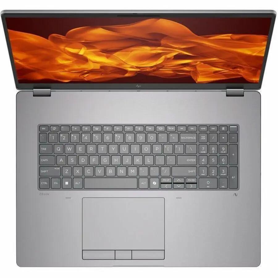 HP ZBook Fury 18 Mobile Workstation laptop, silver body, black keyboard, orange flame wallpaper, top-down view.